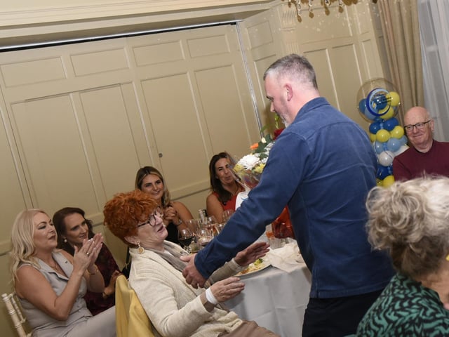 Rory McParland, manager, Greater Shantallow Area Partnership, presents a bouquet of flowers to Anne McDaid, wife of GSAP founding member Charlie, at Friday night's event. : .