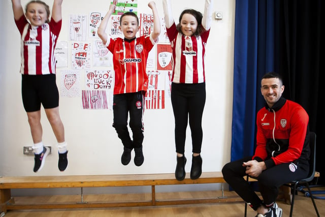 JUMPING FOR JOY: Three Steelstown Primary School pupils jumping for joy at the visit of Derry City's Michael Duffy on Tuesday.