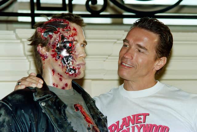 Us Actor Arnold Schwarzenegger poses next to the wax work of his new shape in the movie "Terminator 2" during the 44th Cannes Film Festival in Cannes on May 13, 1991. He also promotes promotes the Planet Hollywood restaurants. (Photo by Jacques DEMARTHON / AFP) (Photo by JACQUES DEMARTHON/AFP via Getty Images)