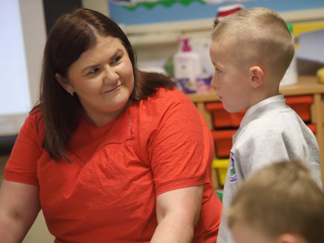 Classroom Assistant Cathy in conversation with P1 pupil Caiden at Sacred Heart PS.