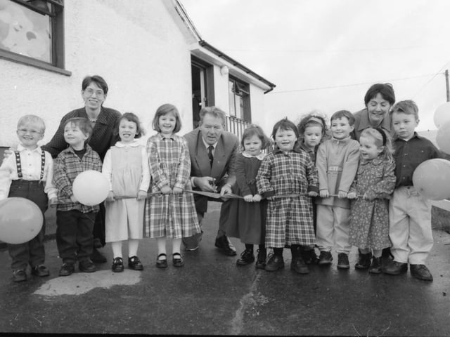 RTÉ broadcaster Mícheál Ó Muircheartaigh, assisted by pupils, cuts the ribbon at the official opening of Naíscoil Dhomnach Óg, at Cashel, Carndonagh. Included, Ríonach Ní Scolaí and Síofra nic an Bhreithiún