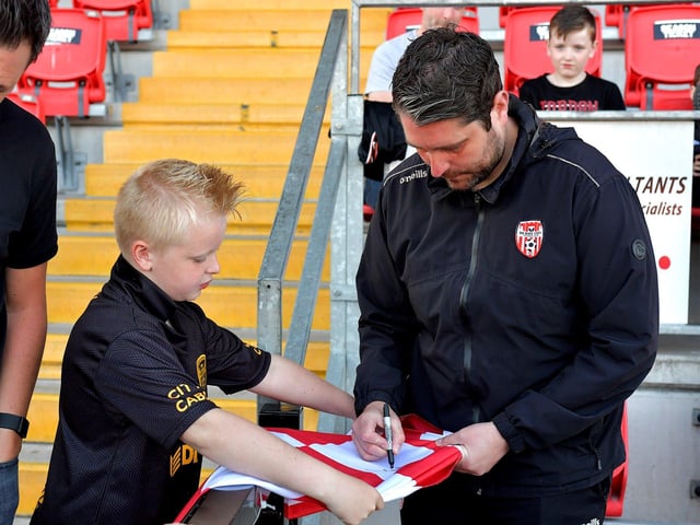 Derry City manager Ruaidhri Higgins signs a shirt for a young fan before the game against Shelbourne on Friday night. Photo: George Sweeney. DER2321GS - 57