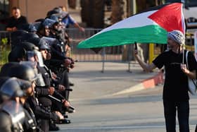 LOS ANGELES, CALIFORNIA - MAY 12: A pro-Palestinian protestor walks along a line of LAPD officers outside Pomona College's commencement ceremony at Shrine Auditorium on May 12, 2024 in Los Angeles, California. The ceremony was relocated from the Pomona College campus to Shrine Auditorium with pro-Palestinian protestors, who are calling for the school to divest from Israeli-tied interests, occupying the main commencement stage since May 5. (Photo by Mario Tama/Getty Images)