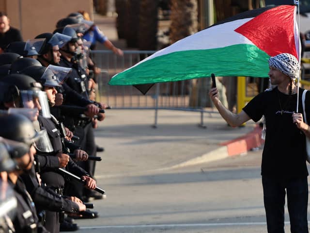 LOS ANGELES, CALIFORNIA - MAY 12: A pro-Palestinian protestor walks along a line of LAPD officers outside Pomona College's commencement ceremony at Shrine Auditorium on May 12, 2024 in Los Angeles, California. The ceremony was relocated from the Pomona College campus to Shrine Auditorium with pro-Palestinian protestors, who are calling for the school to divest from Israeli-tied interests, occupying the main commencement stage since May 5. (Photo by Mario Tama/Getty Images)