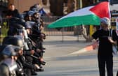 LOS ANGELES, CALIFORNIA - MAY 12: A pro-Palestinian protestor walks along a line of LAPD officers outside Pomona College's commencement ceremony at Shrine Auditorium on May 12, 2024 in Los Angeles, California. The ceremony was relocated from the Pomona College campus to Shrine Auditorium with pro-Palestinian protestors, who are calling for the school to divest from Israeli-tied interests, occupying the main commencement stage since May 5. (Photo by Mario Tama/Getty Images)
