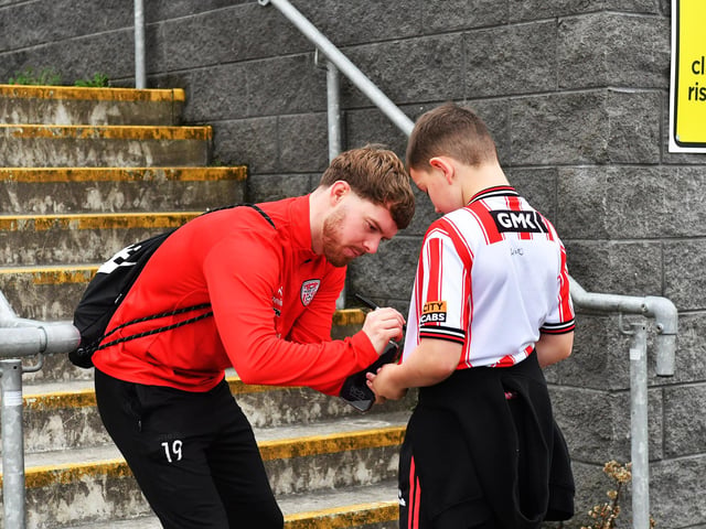 Derry City’s Jacob Davenport signs a shirt for a young fan on Saturday morning prior to the team’s departure for Dublin ahead of Sunday’s FAI Cup Final against Drogheda United. Photograph: George Sweeney.