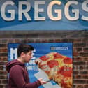 A pedestrian passes a sign for a Greggs bakery in central London on March 5, 2024. (Photo by JUSTIN TALLIS/AFP via Getty Images)