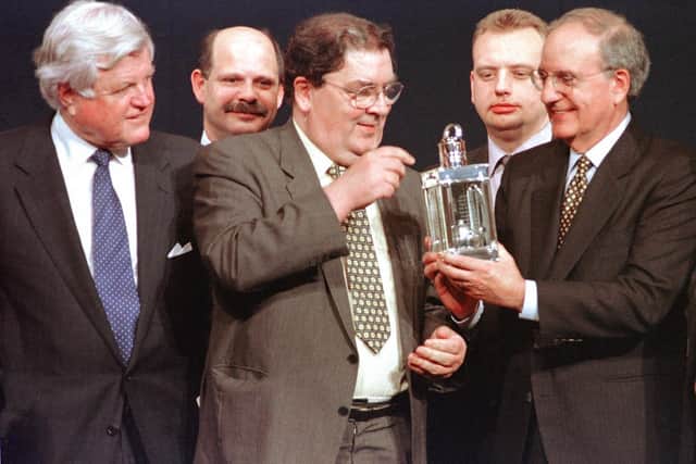 US Senator Ted Kennedy of Massachusetts (L) watches as Nobel Peace Prize winner John Hune (C) looks over the John F. Kennedy Profile in Courage award he was awarded along with former US Senator George Mitchell (R), who chaired the Irish peace talks, David Ervine of the Irish Progressive Unionist Party (L back), and Gary McMichael (R back) of the Irish Ulster Democratic Party during a ceremony at the Kennedy Library in Boston, Massachusetts. AFP PHOTO/John MOTTERN (Photo by JOHN MOTTERN / AFP) (Photo by JOHN MOTTERN/AFP via Getty Images)