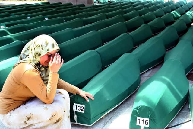 A Bosnian woman weeps next to the coffins of Muslim men and boys before their burial in Potocari, near Srebrenica, East Bosnia and Herzegovina, 11 July 2004. The recently identified remains of 338 Muslim men, aged from 15 to 70, were buried in a common funeral, marking the ninth anniversary of the massacre of Srebrenica, Europe's worst atrocity since World War II. More than 7,000 Muslim men and boys were separated from their women and killed by Serb forces in mass executions, following the Serb capture of the United Nations "Safe Haven Zone" in Srebrenica in July 1995.  Around 20,000 people attended the funeral. (Photo by STRINGER / AFP) (Photo by STRINGER/AFP via Getty Images)