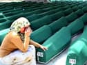 A Bosnian woman weeps next to the coffins of Muslim men and boys before their burial in Potocari, near Srebrenica, East Bosnia and Herzegovina, 11 July 2004. The recently identified remains of 338 Muslim men, aged from 15 to 70, were buried in a common funeral, marking the ninth anniversary of the massacre of Srebrenica, Europe's worst atrocity since World War II. More than 7,000 Muslim men and boys were separated from their women and killed by Serb forces in mass executions, following the Serb capture of the United Nations "Safe Haven Zone" in Srebrenica in July 1995.  Around 20,000 people attended the funeral. (Photo by STRINGER / AFP) (Photo by STRINGER/AFP via Getty Images)