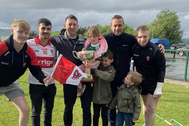 Na Magha coach Ciaran McCarron is proudly pictured with the Richie McElligott Cup, three of the Na Magha players from Ryan O'Neill's squad, his brother Mal and their families.