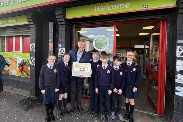 The junior leadership team at Holy Child Primary School presenting a farewell cake to Eamon McKeever upon his retirement.