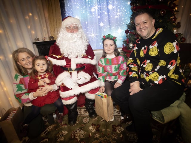 One of the many families getting a photo and collecting a present from Santa on Saturday at Derry Credit Union. : .