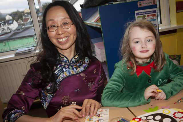 Pupils Sara gets some help with her Chinese mask from Cui.