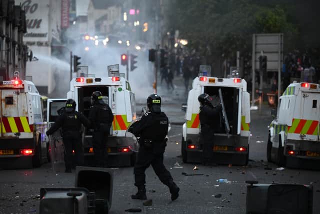 BALLYMENA, NORTHERN IRELAND - JUNE 10: PSNI officers stand behind armoured police vehicles as protesters throw projectiles and start fires on June 10, 2025 in Ballymena, Northern Ireland. (Photo by Charles McQuillan/Getty Images)