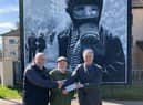 L-R Bogside Artists Kevin Hasson and Tom Kelly receiving a grant from Martin Galvin on behalf of the AOH in the US.