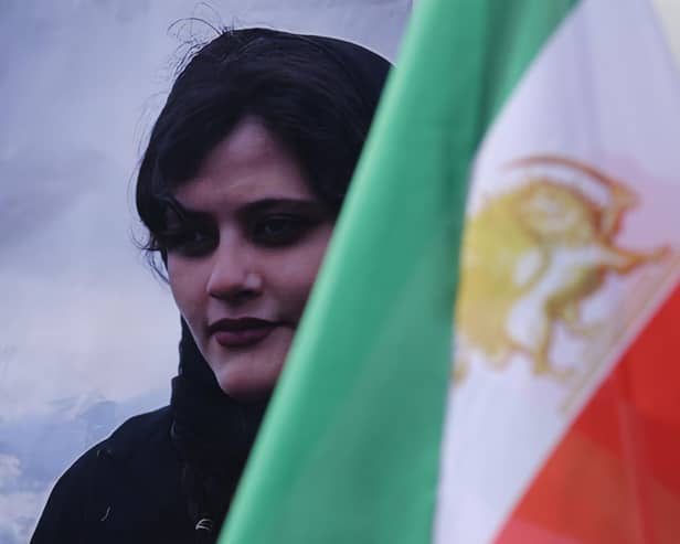 A portrait of Mahsa Amini stands next to an Iranian opposition flag during a protest gathering of supporters of the National Council of Resistance of Iran, an Iranian opposition group based abroad, on September 28, 2022 in Berlin, Germany. Amini, 22, was arrested by Iranian authorities in Tehran on September 13, 2022, for not wearing her headscarf properly and died three days afterwards, apparently due to a severe head injury. Her death has sparked demonstrations in Iran nationwide that have spiralled into violence between protesters and police and left dozens of protesters dead. (Photo by Sean Gallup/Getty Images)