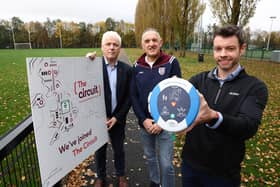 John Deery (centre) from Eglinton survived a cardiac arrest at this year’s Belfast Marathon thanks to a life-saving defibrillator and CPR performed by Peter O’Hare (right holding the defib,). John and Peter are pictured alongside Head of British Heart Foundation NI’s Fearghal McKinney.