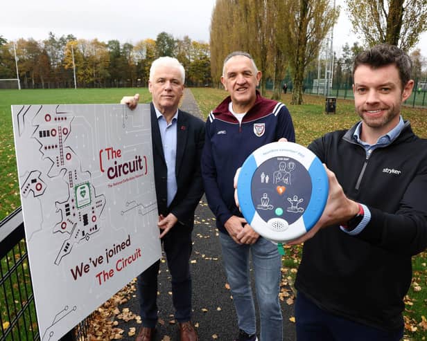 John Deery (centre) from Eglinton survived a cardiac arrest at this year’s Belfast Marathon thanks to a life-saving defibrillator and CPR performed by Peter O’Hare (right holding the defib,). John and Peter are pictured alongside Head of British Heart Foundation NI’s Fearghal McKinney.