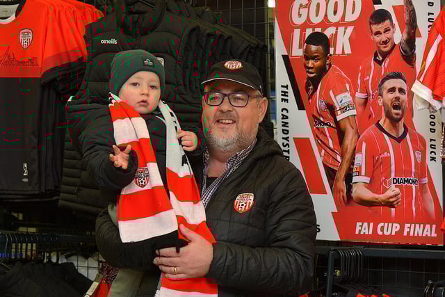 Two year old Cai Cairns and Michael Barr record a good luck video message for the Derry City team at O’Neill’s Sports store ahead of their FAI Cup final against Shelbourne. DER2244GS – 106