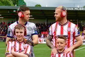 Derry City goalkeeper Brian Maher and defender Mark Connolly wearing their ear defenders alongside Ardnashee pupils and mascots ahead of kick-off on Friday night.