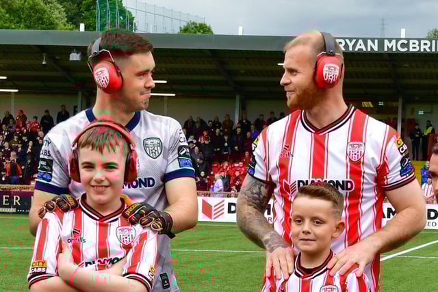 Derry City goalkeeper Brian Maher and defender Mark Connolly wearing their ear defenders alongside Ardnashee pupils and mascots ahead of kick-off on Friday night.