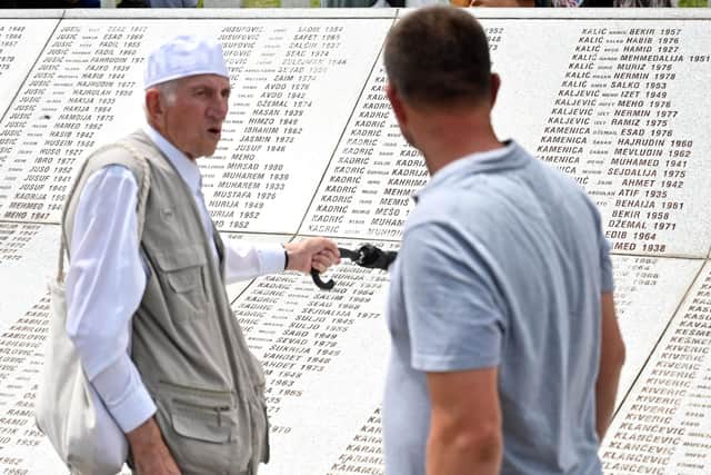 Bosnian Muslims pass by the memorial wall during a mass burial of victims of the 1995 Srebrenica massacre, at the memorial cemetery in the village of Potocari, near eastern Bosnian town of Srebrenica, on July 11, 2022. - During the collective burial, on the 27th anniversary, 50 newly identified bodies were placed in their final resting place at the Potocari memorial. (Photo by ELVIS BARUKCIC / AFP) (Photo by ELVIS BARUKCIC/AFP via Getty Images)