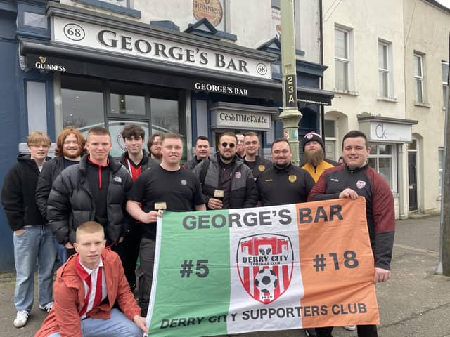 Derry City fans proudly display their flag outside George's Bar before heading on the bus to Dublin.