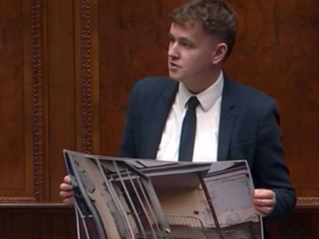 Pádraig Delargy holding up photographs of dilapidated schools in Derry in Stormont on Tuesday as he called for greater investment in the schools estate in the city.