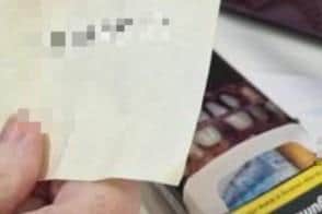 The pensioner displaying a post-it note with a a telephone number on it that was found in a cigarette box that also contained £500.