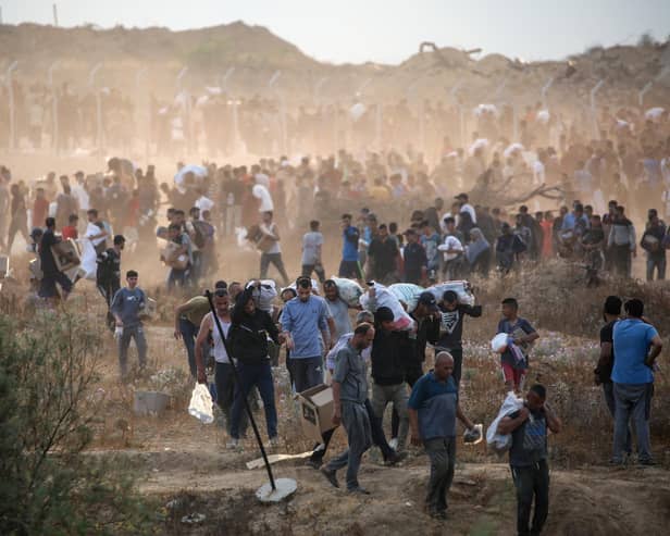 People carry relief supplies from the Gaza Humanitarian Foundation (GHF), a private US-backed aid group that has bypassed the longstanding UN-led system in the territory, as displaced Palestinians return from an aid distribution centre in the central Gaza Strip on June 8, 2025. The UN and major aid organisations have refused to cooperate with the GHF, citing concerns that it was designed to cater to Israeli military objectives. (Photo by Eyad BABA / AFP) (Photo by EYAD BABA/AFP via Getty Images)