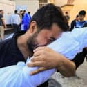 A Palestinian man reacts while holding the body of a relative killed following Israeli bombardment, during a funeral service in Deir Al-Balah in the central Gaza Strip on October 31, 2023. (Photo by Mahmud HAMS / AFP) (Photo by MAHMUD HAMS/AFP via Getty Images)