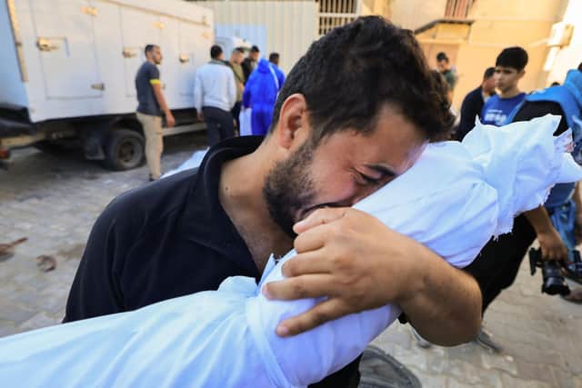 A Palestinian man reacts while holding the body of a relative killed following Israeli bombardment, during a funeral service in Deir Al-Balah in the central Gaza Strip on October 31, 2023. (Photo by Mahmud HAMS / AFP) (Photo by MAHMUD HAMS/AFP via Getty Images)