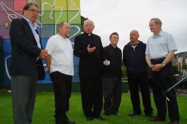 2004 Left to right: The late John Hume, Bogside Artist Tom Kelly, the late Bishop Edward Daly, the late Bogside Artist William Kelly, Bogside Artist Kevin Hasson, and the late Martin McGuinness pictured at the launch of the People's Gallery following the completion of the final 'Peace' mural. (Photo: Bogside Artists)