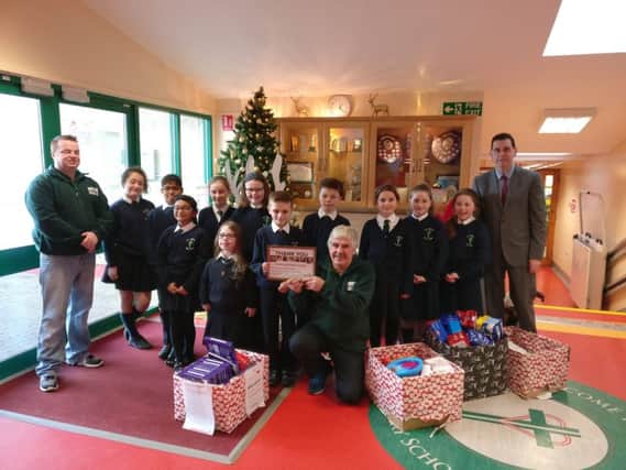 Children from Good Shepherd Primary School handing over their food donations to staff from the Foyle Foodbank.