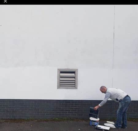 Sinn Fein activist painting over the graffiti at the weekend.
