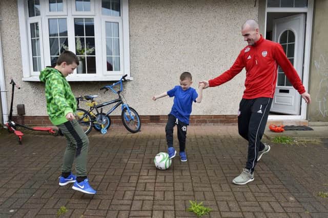 Gerard Doherty playing  kickabout with his sons Lennan (11) and Cian (5) at their family home in Creggan. DER1818GS046