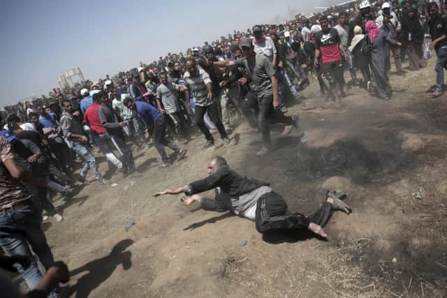 An elderly Palestinian man falls on the ground after being shot by Israeli troops during a deadly protest at the Gaza Strip's border with Israel, east of Khan Younis, Gaza Strip, Monday, May 14, 2018. Thousands of Palestinians are protesting near Gaza's border with Israel, as Israel celebrates the inauguration of a new U.S. Embassy in contested Jerusalem. (AP Photo/Adel Hana)