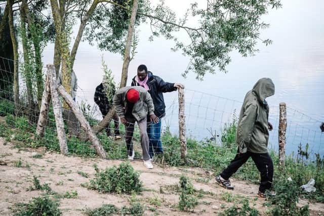 Migrants attempting to scale a camp fence.