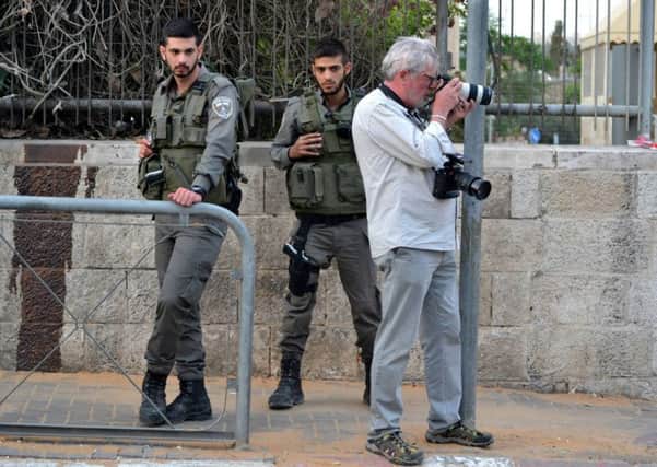 John McColgan taking photographs in Jerusalem as Israeli soldiers look on