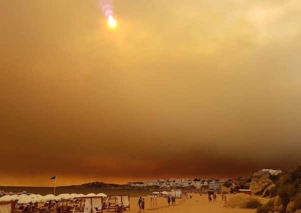The wildfires send ash clouds over Albufeira's main beach on Wednesday.
