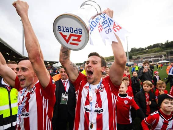 Derry City's Ben Fisk holds aloft the EA Sports Cup.