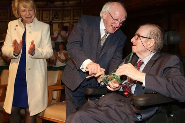 President Michael D. Higgins makes a presentation to Ivan Cooper as his wife Sabina looks on.