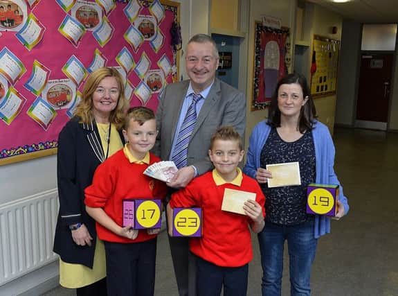 Franz Schlindwein, creator of IZAK9, presents Shea McCarthy with Â£500 cash after the Steelstown Primary School pupil won the Sum Craic Maths Quest at Foyleside Shopping Centre. Included are Mrs Siobhan Gillen, principal, pupil Derry Doherty, a runner-up who won a Â£50 Foyleside voucher, and classroom assistant Terri Henry who also won a Â£50 Foyleside voucher. DER4318GS011