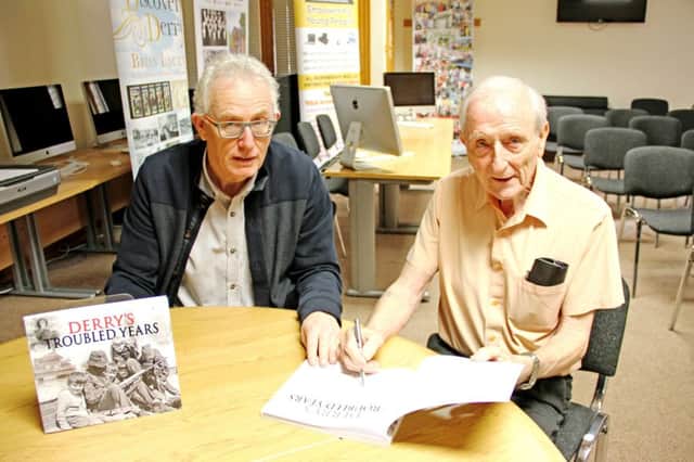 Eamon Melaugh signs a copy of Derrys Troubled Years for Creggan Enterprises director Conal McFeely.