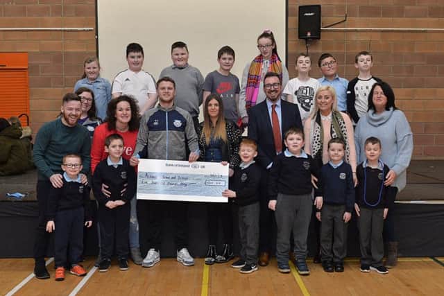 AJ and Mary Jane McClean present a cheque donation for £500, on behalf of James McClean, to Ardnashee School and College PE teacher Eamon Colhoun. Included in the picture are acting Principal Mr Raymond McFeeters, pupils, staff and parents. The generous donation is a contribution towards equipping a new gym. DER0519GS-029