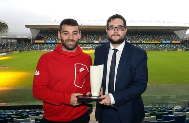 Larne's David McDaid collects the Belleek trophy from NIFWA Chairman Keith Bailie.