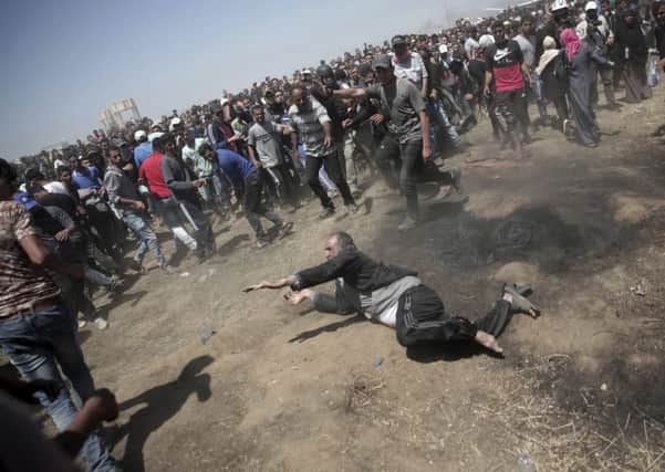 An elderly Palestinian man falls on the ground after being shot by Israeli troops during a deadly protest at the Gaza Strip's border with Israel, east of Khan Younis, Gaza Strip on May 14, 2018. Thousands of Palestinians were protesting near Gaza's border with Israel, as Israel celebrates the inauguration of a new U.S. Embassy in contested Jerusalem. (AP Photo/Adel Hana)