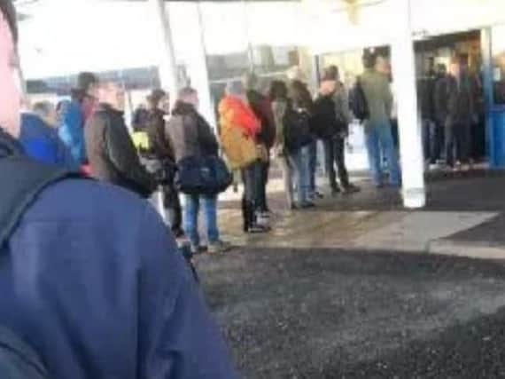 A line of passengers queue outside the main terminal building at Belfast International Airport on Monday.