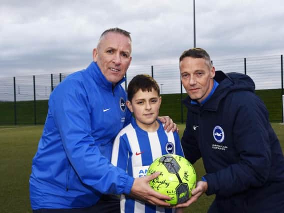 Jude McCourt presenting a football signed by Foyle Harps Youth Football Club players to Brighton & Hove Albion academy coach Patrick Rocks, right, when he took a coaching session at Leafair on Friday evening. Included is Leroy McCourt. DER1419-110KM
